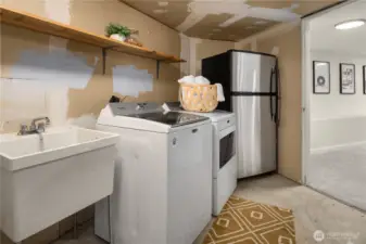 The full sized laundry room features a laundry sink and great storage. More storage is unseen to the right.