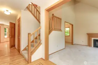 A nice view of the stairway leading up to the upper level and the living room with gas fireplace. Dining room is through the living room to the left.