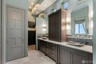 The primary spa bath offers heated marble floors, dual vanities with custom cabinetry, a limestone soaking tub, walk-in shower, separate water closet, and a spacious walk-in closet — designed for comfort, privacy, and everyday indulgence.