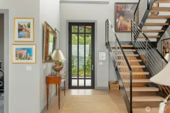 A sculptural open-metal staircase with solid wood treads, precisely matched to the French Oak flooring, creates a striking architectural focal point upon entry.