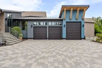 Oversized three-bay garage with exceptional ceiling height and depth, offering flexible space for indoor boat or RV storage, a car lift, or the ultimate showcase garage.    The expansive custom paver driveway creates a grand motor court feel while providing abundant space for guest parking or dedicated outdoor RV parking — all framed by the home’s striking modern coastal architecture.