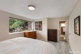 Another view of the primary suite with picturesque, calming views through the huge windows! The doorway to the ensuite is straight ahead.