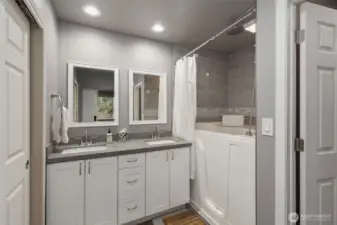 This beautifully updated full bath connected to the second main-floor bedroom features a convenient walk-in tub with overhead shower and tiled surround. Double vanities and large closet on the right complete this spa-like space.