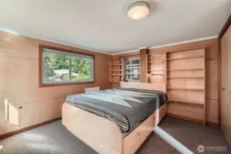 The primary bedroom is located off the open water channel, with built in bes, drawers below and a wall of book/decor shelving. Add baskets for additional storage. The closet is to the right.