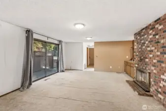 View of family room from kitchen, patio doors to your right lead to your patio, double-sided natural fireplace to your right. Straight ahead is your utility room, another bedroom and garage entrance.