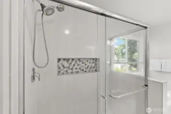 A decorative tiled inlaid shower shelf provides a place for shower essentials for a clutter free floor.