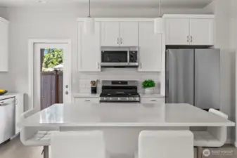 A vision in white—counters, tile, and cabinetry blend seamlessly for a crisp, modern aesthetic, subtly contrasted by the sleek elegance of stainless steel appliances