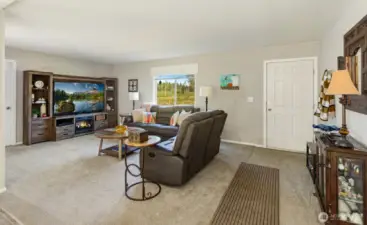 The spacious living room features plush carpet, abundant natural light, and an open layout perfect for entertaining or relaxing.