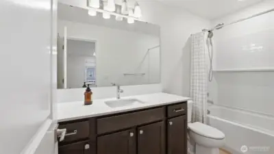 Spacious guest bath featuring a large mirror, abundant cabinet storage, and modern fixtures.