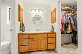 Primary vanity centrally located between the walk-in shower, private toilet room, and closet, offering a convenient and well-connected layout.
