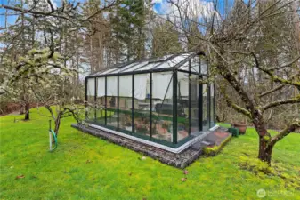 Greenhouse sits next to raised garden beds on this 1.2+ acre lot