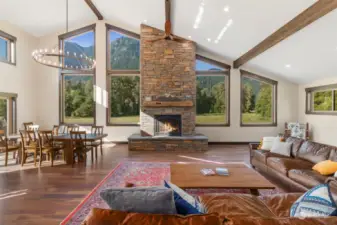 A striking double-sided stone fireplace anchors the great room, seamlessly connecting the living and dining areas. Rich hardwood floors throughout.