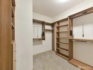 Primary attached closet with shelving and built-in drawers.