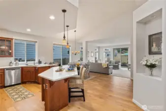 The heart of the home shines in this bright, open-concept kitchen and living area. Warm wood cabinetry and gleaming quartz countertops lend the kitchen a timeless elegance.