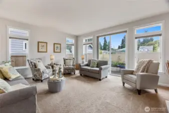 The adjacent dining area flows seamlessly into a comfortable living room with plush carpet and expansive windows, offering an easy connection to the backyard patio. Together, these spaces provide a perfect setting for daily living and effortless entertaining.