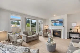 This light-filled living room offers a perfect blend of warmth and style. A gas fireplace with a tile surround and crisp white mantel serves as a focal point, And the TV above the fireplace stays with the home!