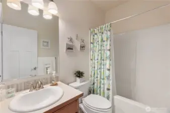 The hall bath has tall ceilings, a neutral color palette and a tub/shower combination.
