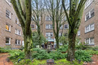 Tucked behind a wrought-iron gate, Garden Court’s central courtyard features brick paths, towering trees, and a fountain—an unexpected pocket of calm in the heart of Capitol Hill.