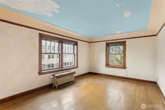 Vintage charm abounds in the living room, with coved ceilings, oak floors, divided-light windows, and generous proportions. The oak floors are well loved but in solid shape, just waiting for a fresh refinish to bring back their original old-growth glow.