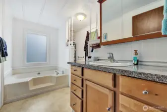 Private, bath off the primary bedroom. Single sink vanity with drawers and cabinets for all your bath necessities. Take a bubble bath an relax in the garden tub. Privacy half wall for the commode area.