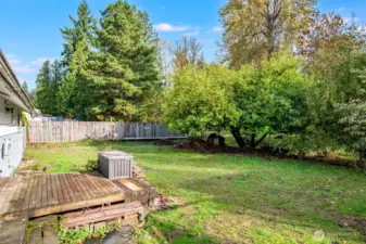 The deck looks out over the lawn and mature fruit trees.