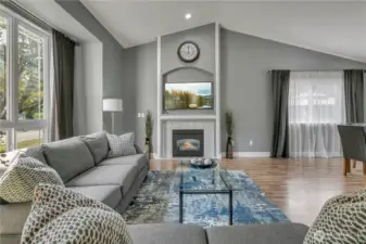 Spacious and open living room with vaulted ceilings, large picture windows allowing ample natural light, and opens to the dining room. Cozy gas fireplace features a charming nook area above. Features newer paint.