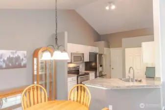 View from the dining room to the kitchen featuring pantry & vaulted ceilings.