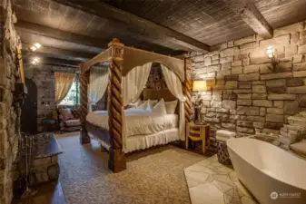 Castle Suite king bed with wood-burning fireplace and soaking tub.