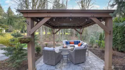 Backyard remodel featuring paver patio, gas fire table, illuminated pagoda with convenient electrical outlets.