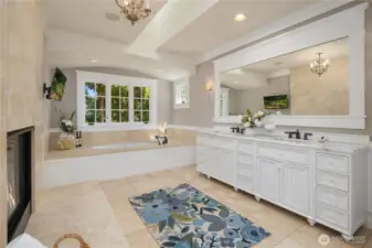 Luxurious spa bathroom with dual sink vanity, soaking tub, radiant heated hearth, and radiant floor heat