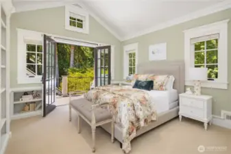 Western bedroom has a vaulted ceiling, built in bookcases and French doors to an upper porch