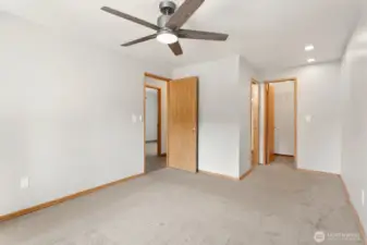 Primary bedroom with walk in closet with cedar accent floor and ceiling fan