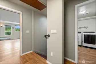 The home offers two separate living spaces, divided by a spacious laundry room equipped with a utility sink. A connecting hallway features a walk-in storage closet, additional wall-mounted storage cupboards, and convenient pull-down attic access with a built-in ladder.