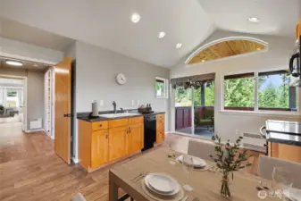 This open-concept living area serves as the second full living space, complete with a full kitchen, attached bath, covered balcony, accessed by sliding glass doors, and a free-standing wood stove—perfect for cozy winter evenings