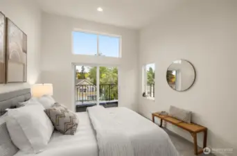 The primary bedroom is a sanctuary of natural light, featuring vaulted ceilings, large windows, and private balcony access. Wake up to serene views and unwind in your peaceful haven. Photos of home with similar layout, finishes & fixtures.