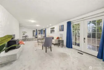 Living room has a wood fireplace insert and french doors leading to the backyard deck.