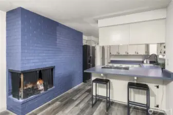 Kitchen has a cozy wood fireplace and eating bar.