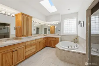 Opulent bathroom with two large vanity areas, soaking tub, and walk in tiled shower. Private   lavatory room off camera.