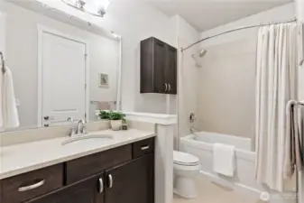Upgraded second full bath with a beautifully tiled shower and rich wood cabinets.