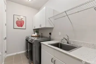 Spacious laundry room with new washer/dryer combo. Includes a convenient deep sink hanging space and enough counter space to fold.