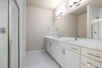 The primary bath has two sinks and an upgraded tile shower w/glass door.