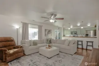 The living room is bright and inviting, with abundant natural light streaming in and a ceiling fan overhead to keep the space comfortable year-round.
