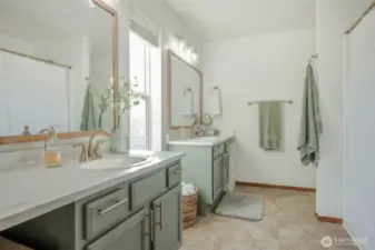 Conveniently located off the primary bedroom, this en suite bathroom includes dual vanities, a shower/tub combo, and bright, even lighting. Modern finishes add a sleek, updated feel to this comfortable and functional space.