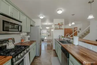 This beautifully designed kitchen features custom butcher block countertops, under-cabinet lighting, stainless steel appliances, a spacious sink, and breakfast bar seating—perfect for entertaining. Just off the kitchen, the dining area offers a seamless flow for easy meals and gatherings, all within an inviting open-concept layout.