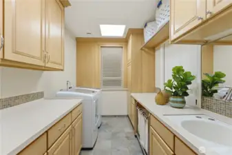 The first laundry room is bright and efficient, featuring generous storage, a sink, and thoughtful organization