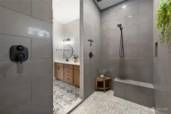 Enormous walk-in shower with bench seating, multiple water heads and window for natural light.