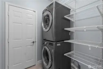 Laundry room features Stackable washer and dryer plus shelving for storage.