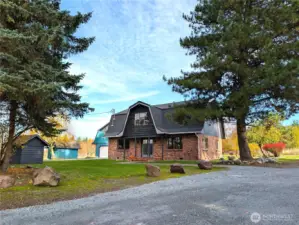 Front of home w/detached garage in the background.  Fresh gravel driveway.