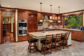 Gourmet kitchen with expansive island, custom cabinetry, and large windows bringing in natural light and serene outdoor views—ideal for gathering and entertaining.