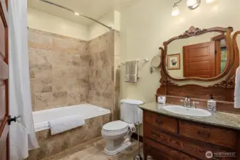 Primary bath with tiled tub/shower surround, granite vanity, and warm wood cabinetry, blending functionality with classic design.